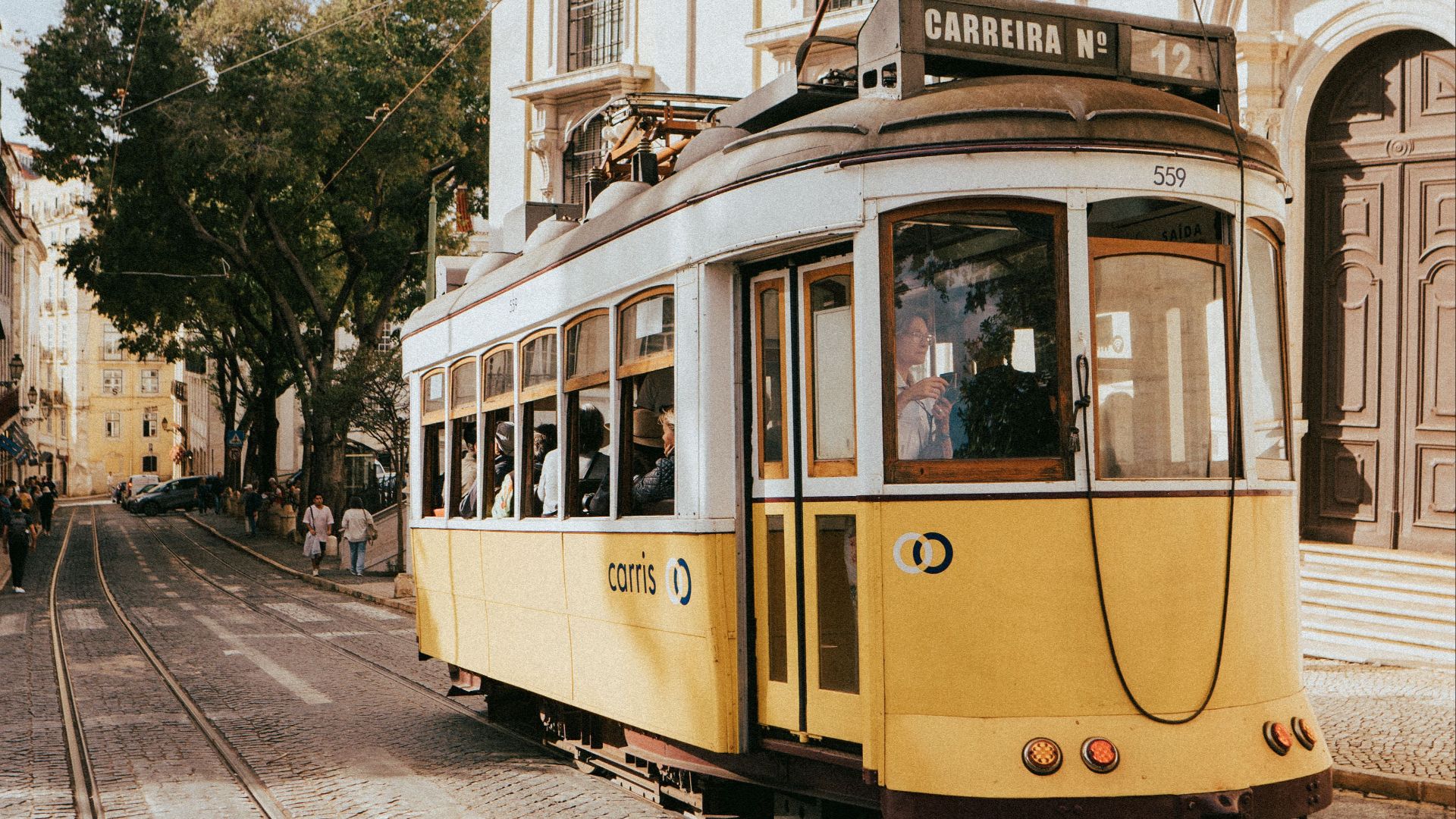 Iconic yellow tram travels through the historic streets of Lisbon, Portugal.