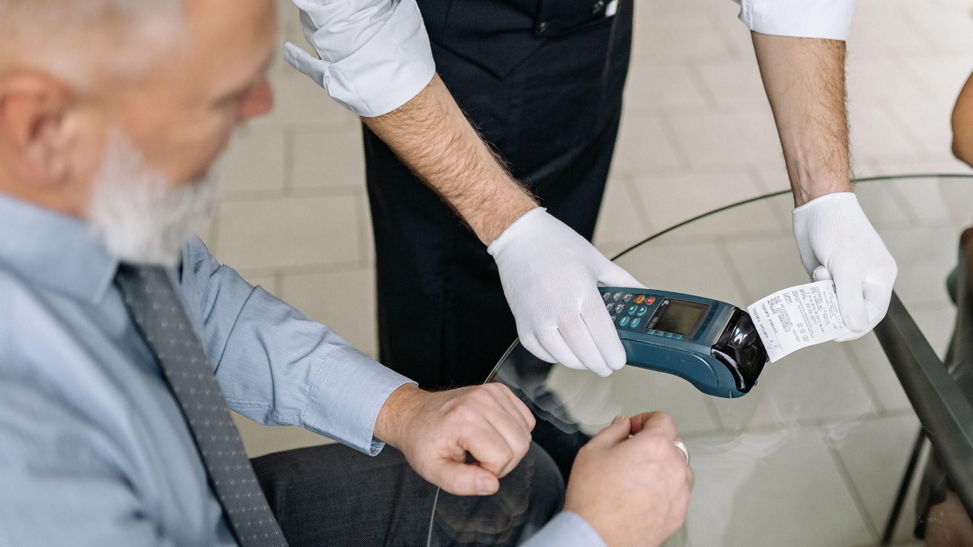 A couple making a contactless payment using a credit card at a restaurant table.