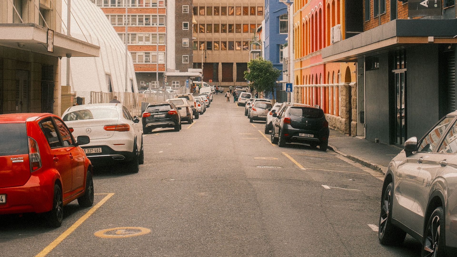Vibrant street scene in downtown Cape Town with colorful buildings and parked cars.