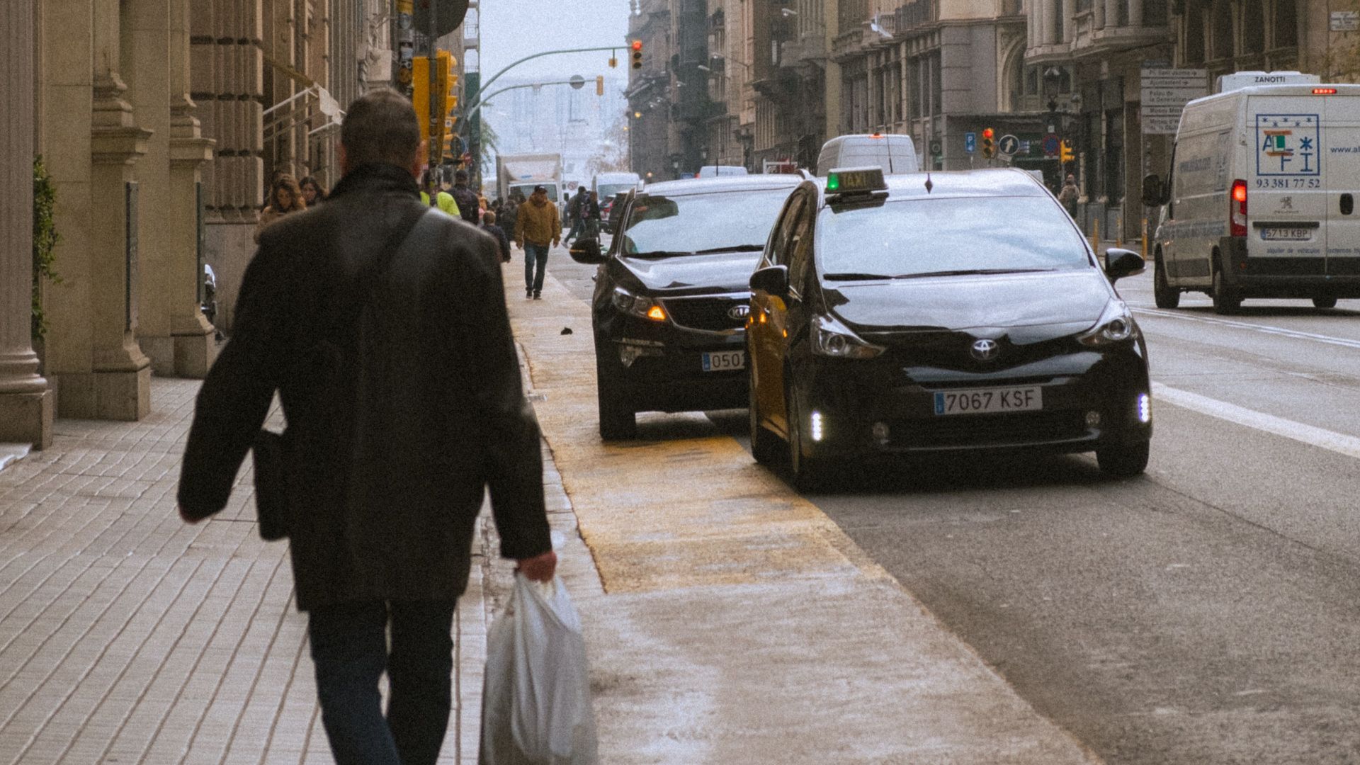 Man walking on a busy street in Barcelona's Gothic Quarter with iconic architecture.