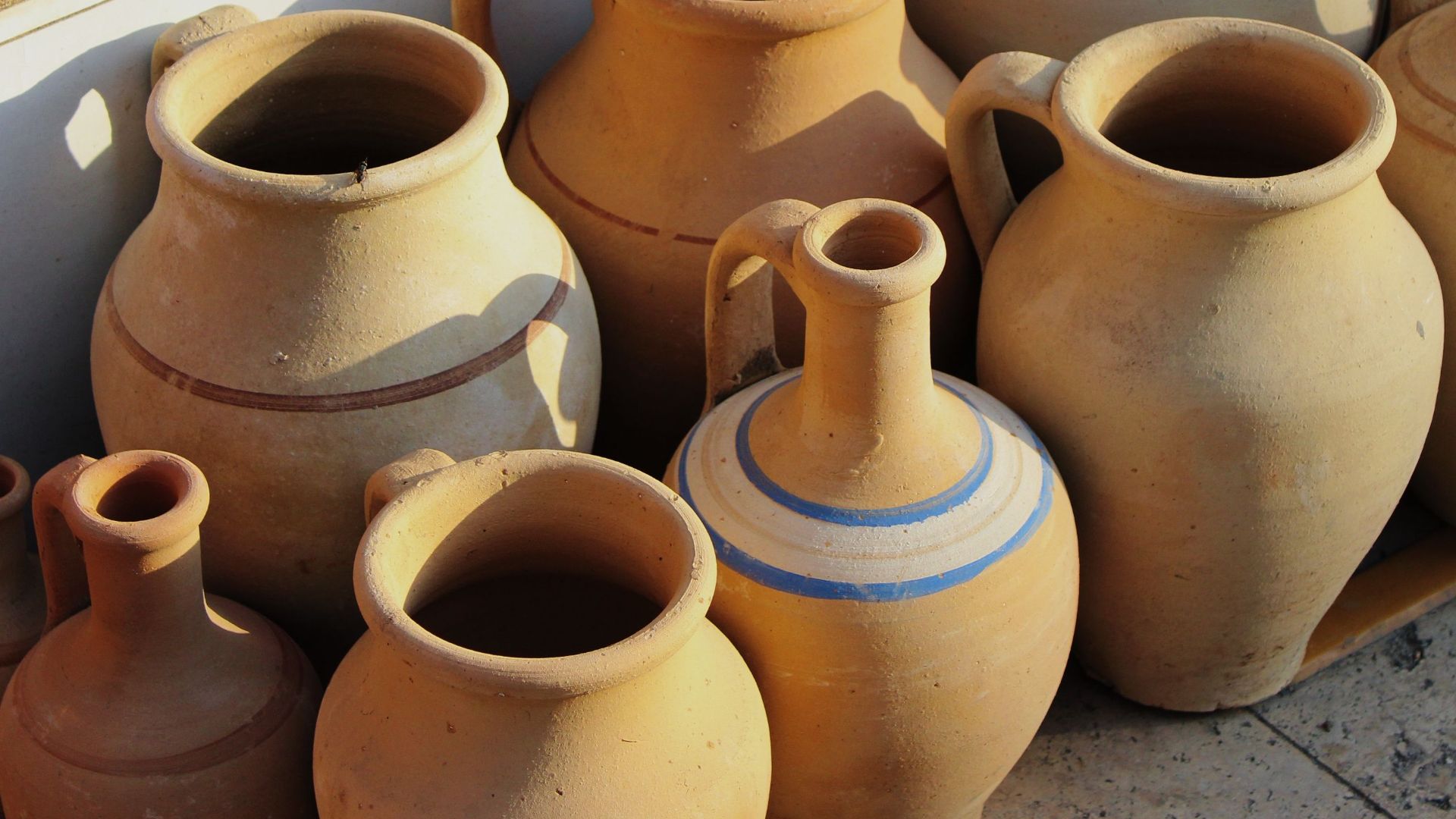 Collection of traditional clay jugs and bowls on display at a market stall.