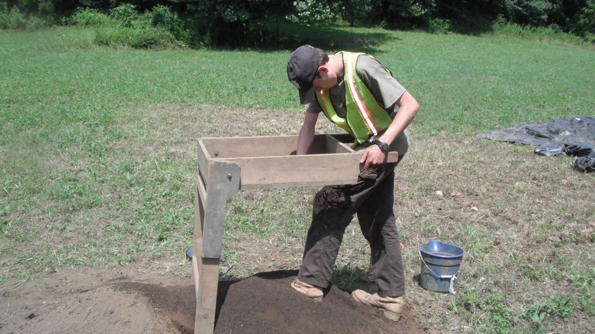 A young man uses a soil sifter to search for artifacts