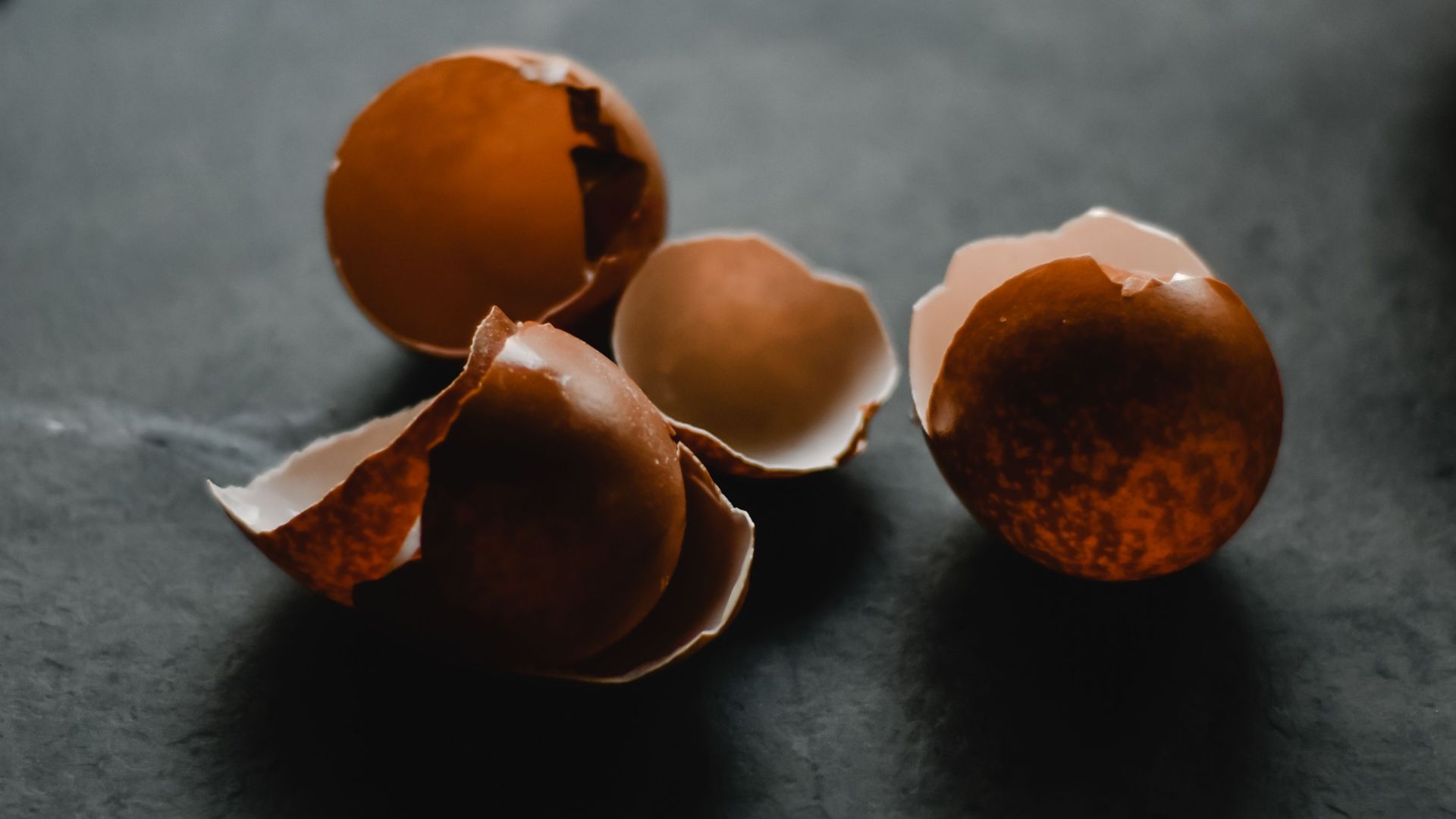 Moody close-up of cracked eggshells with a blurred background, perfect for kitchen themes.
