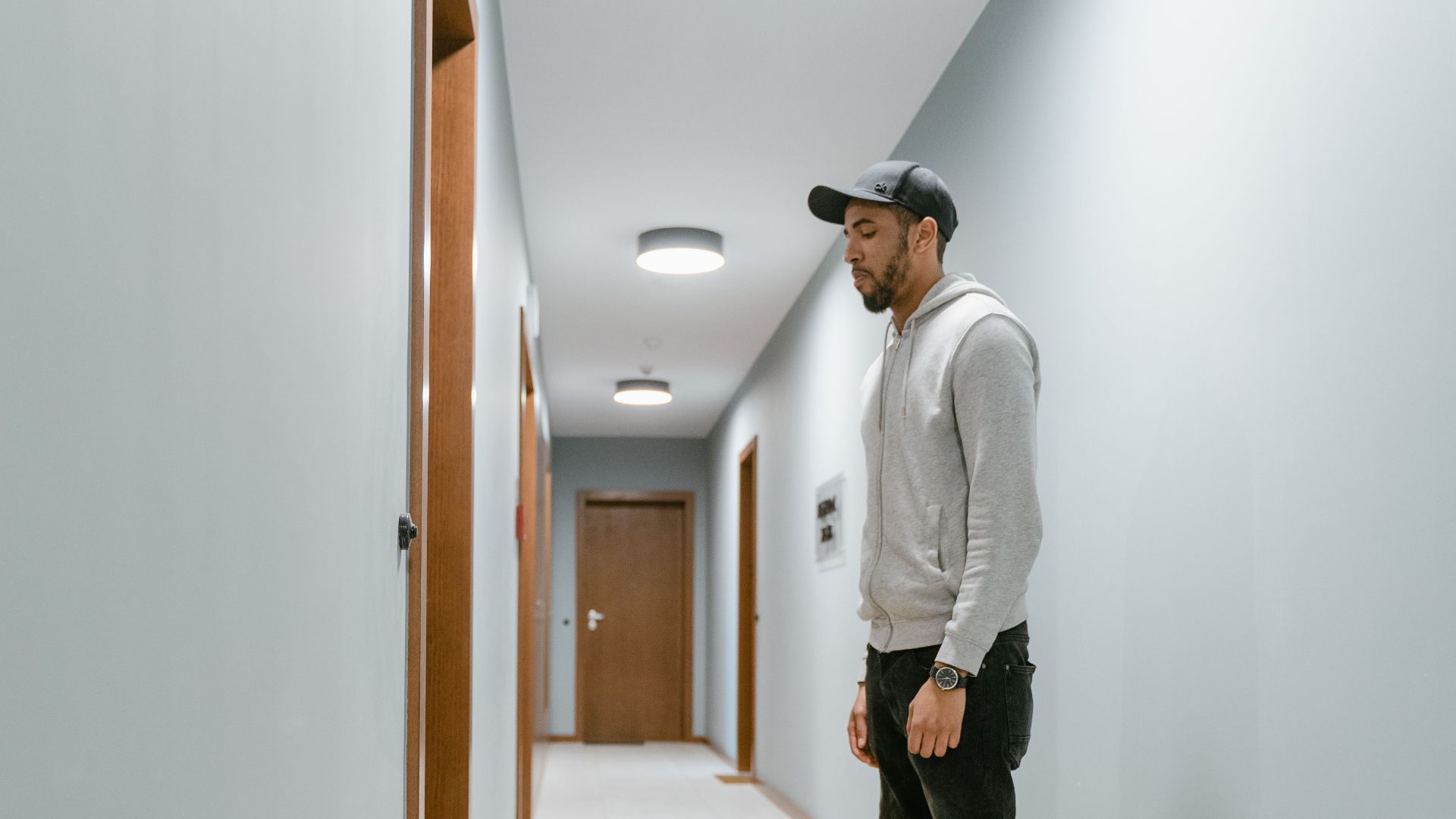 Delivery courier standing in a residential hallway with a yellow bag, waiting to deliver a package.
