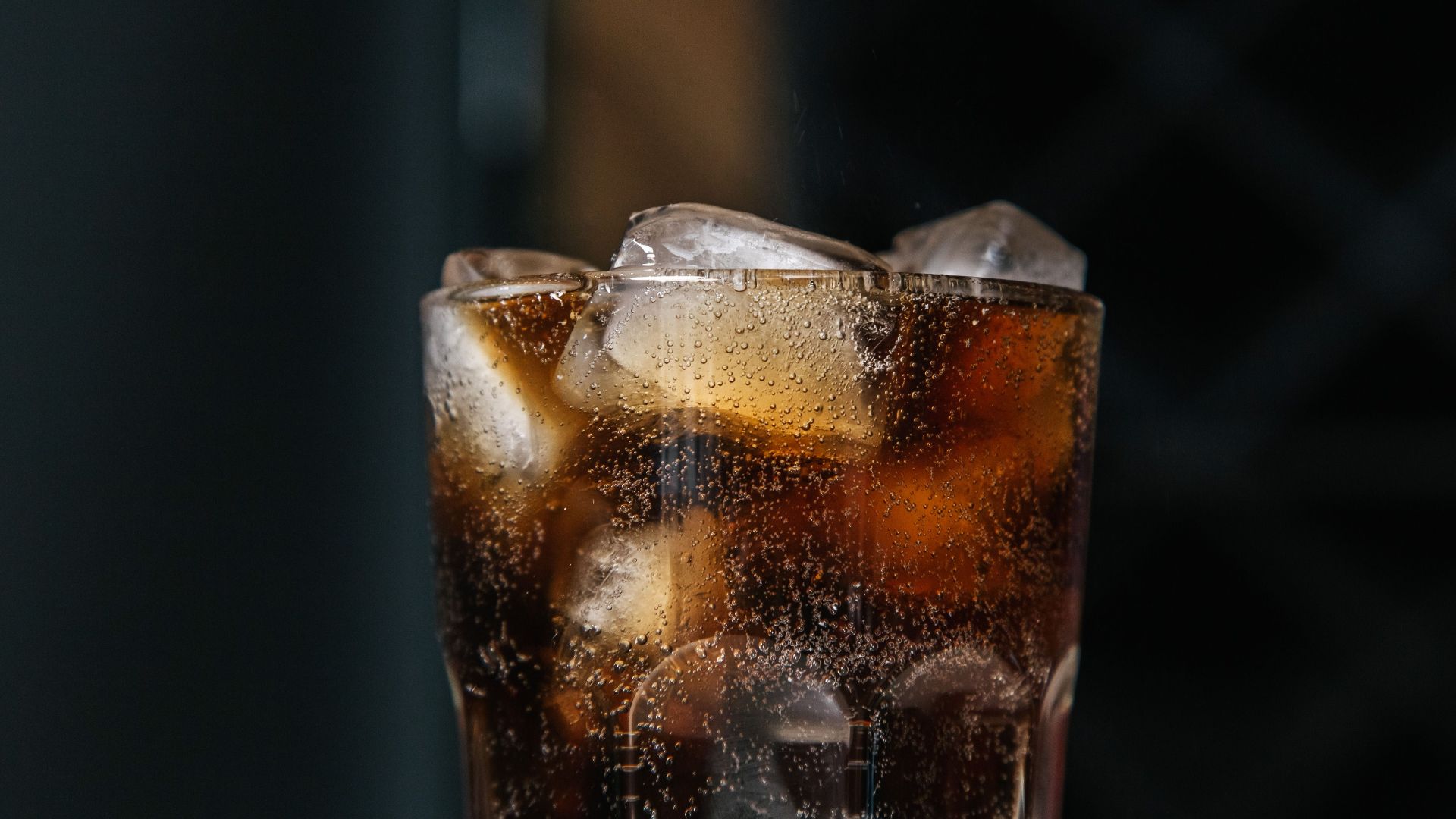 Cooling beverage with fizzy bubbles and ice cubes in a clear glass.