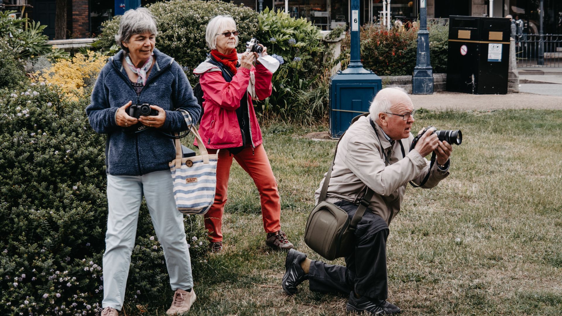 Group of senior tourists taking pictures in an urban park with cameras.