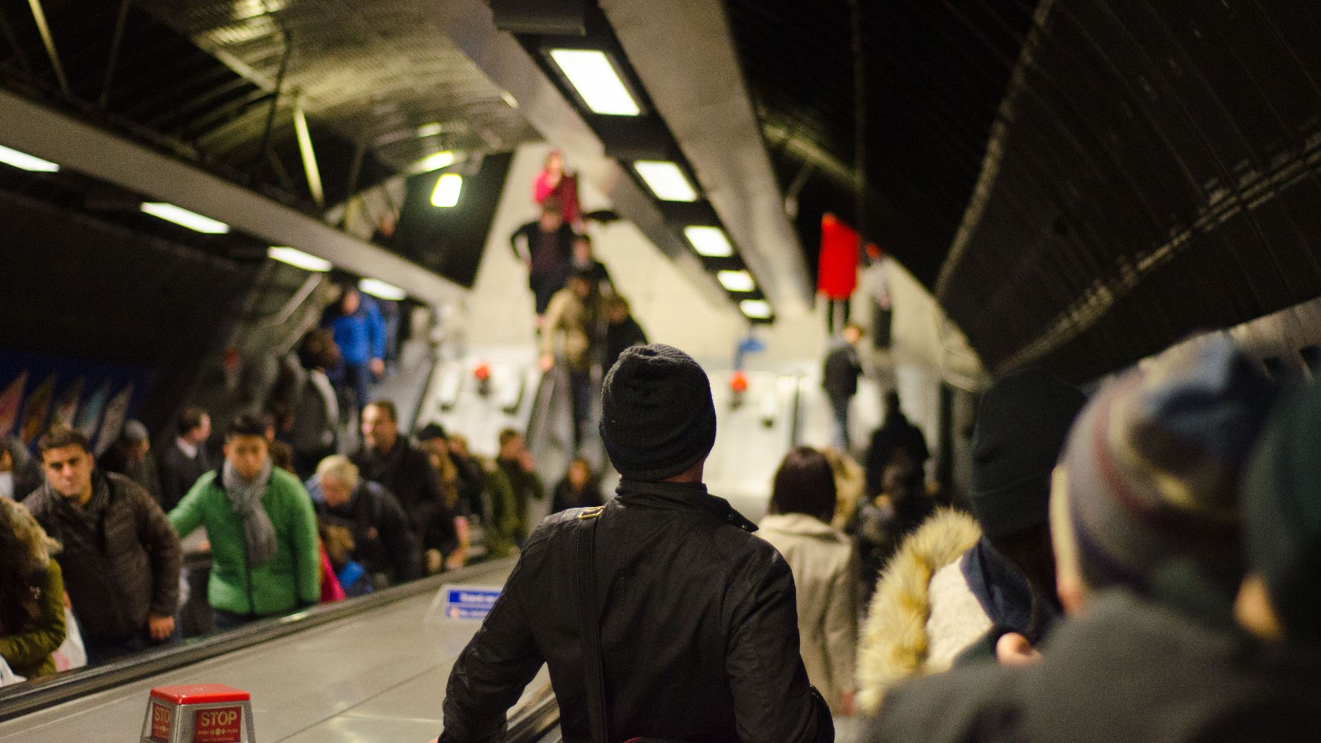 Commuters using crowded escalators in an indoor metro station setting.
