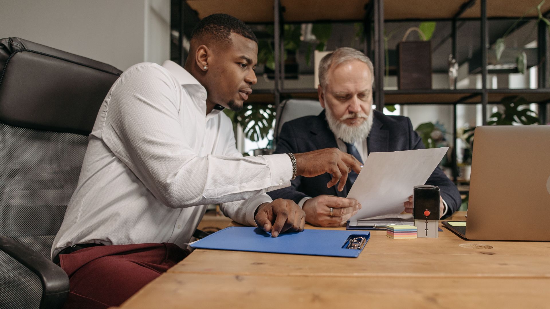 Two businessmen reviewing documents together in a modern office environment.