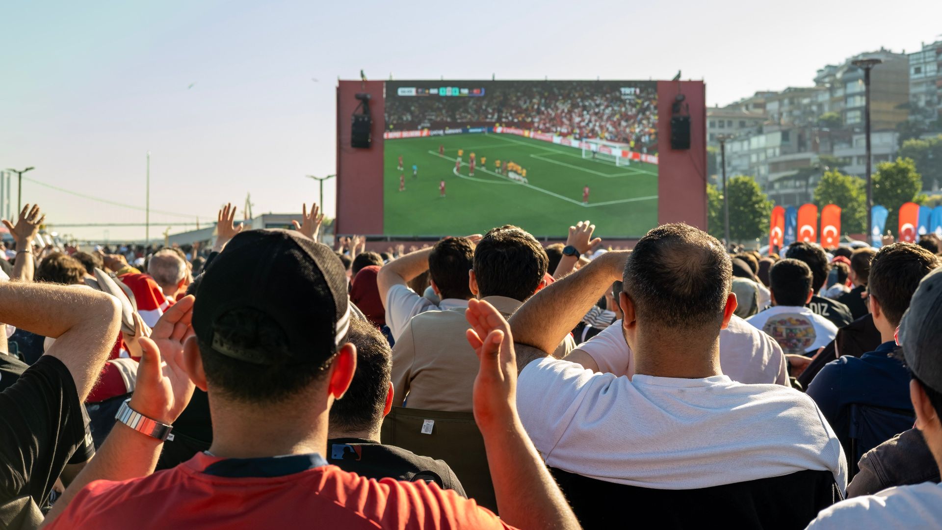 Crowd watching a soccer game on a large screen outdoors in Istanbul, Türkiye.
