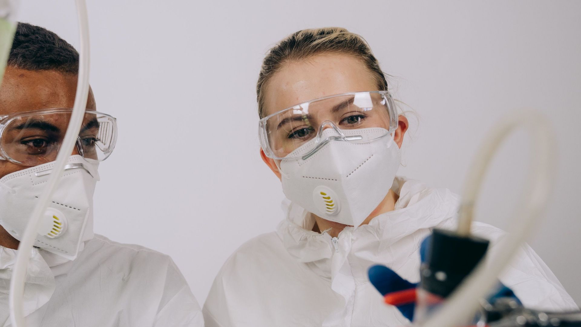 Two scientists conducting research in a lab with protective equipment.