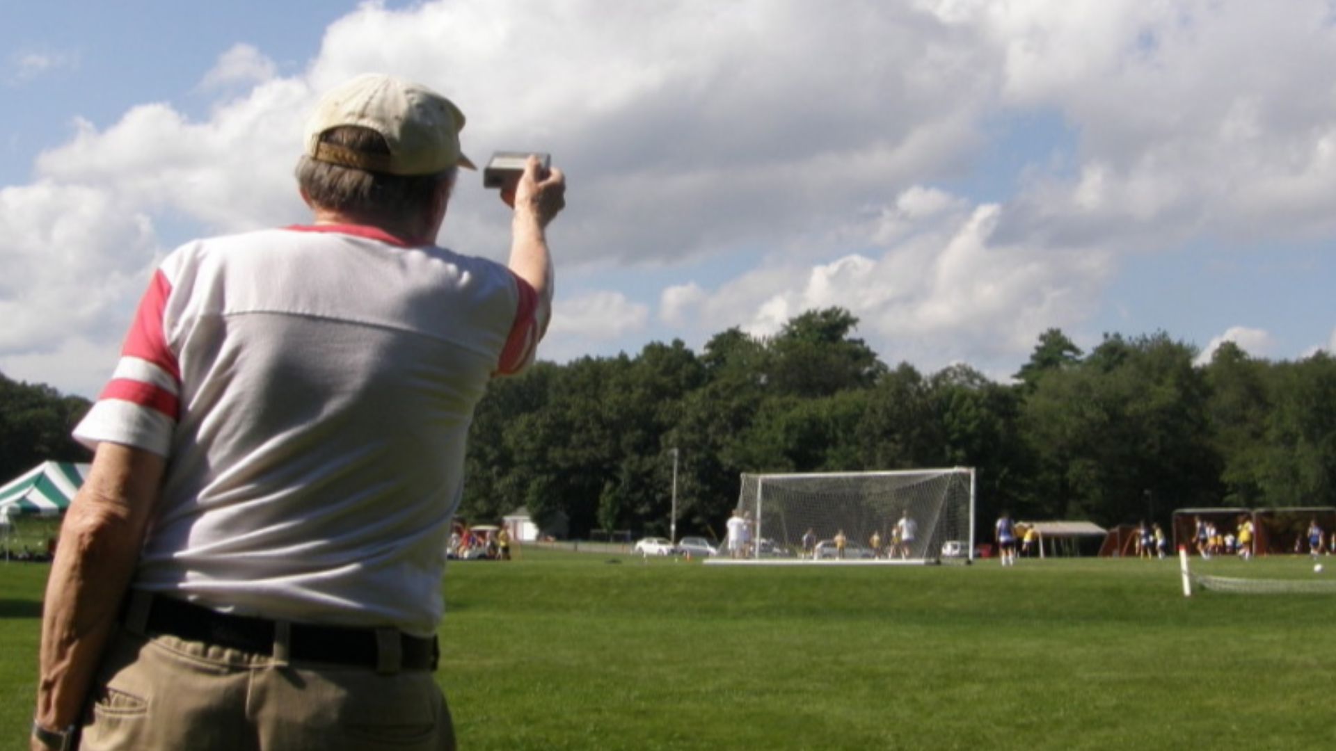 A man at an athletic field using an Airborne Research Associates model M-10 Intracloud Lightning Detector and aiming it at a specific cloud.