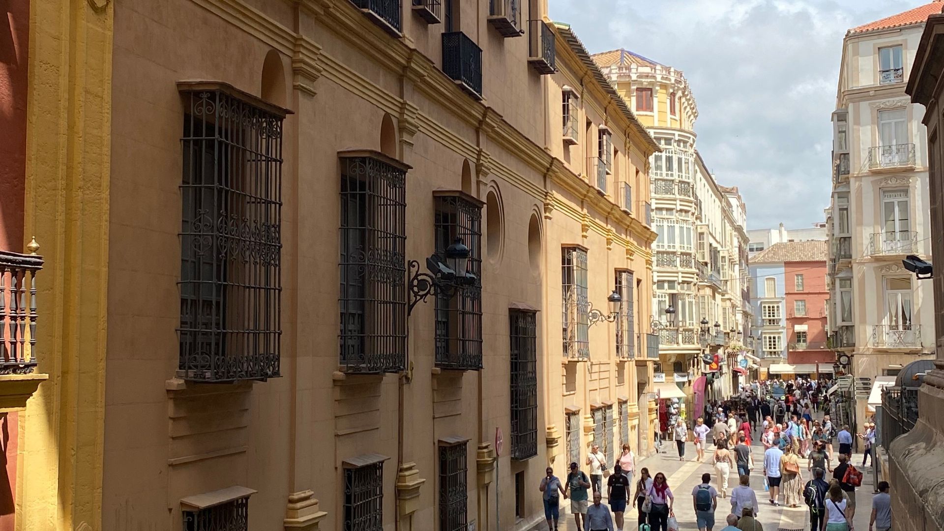 High angle view of a lively street in Málaga, Spain, showcasing historical architecture and vibrant urban life.