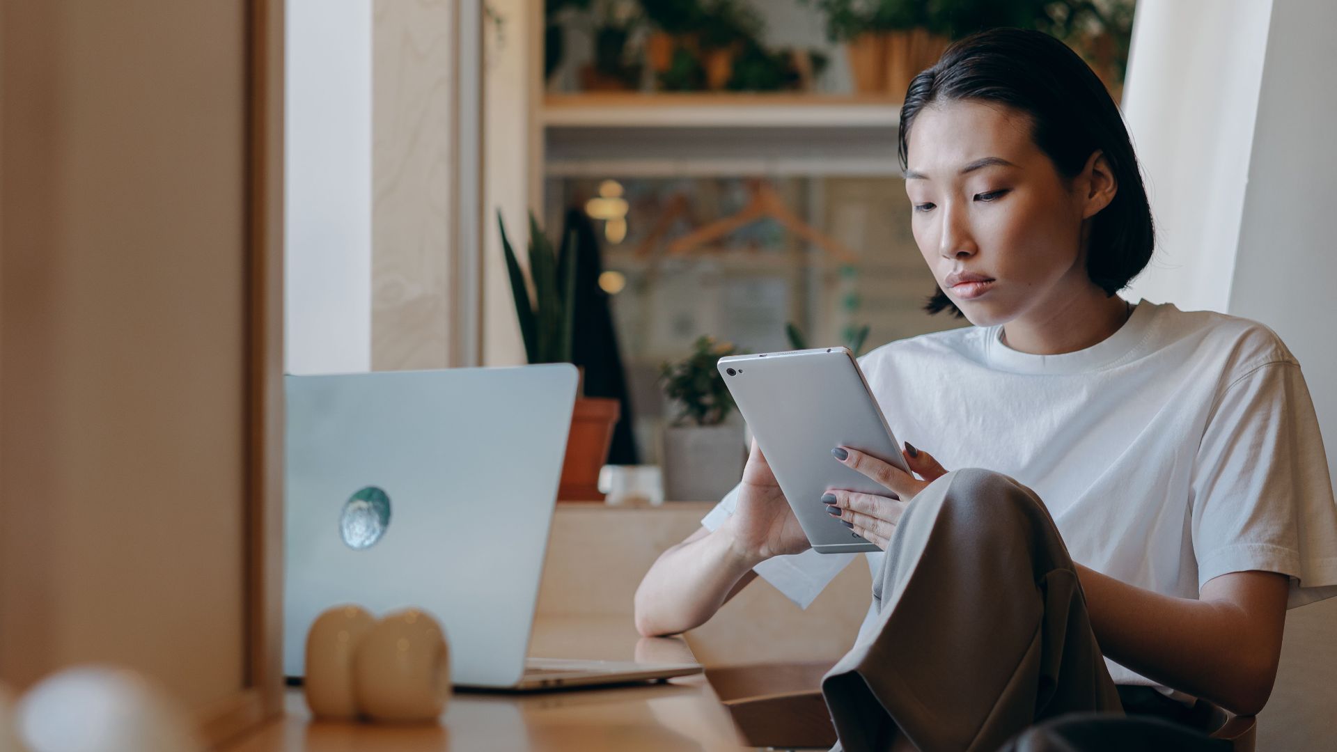 Asian woman using a tablet for remote work in a modern indoor setting.