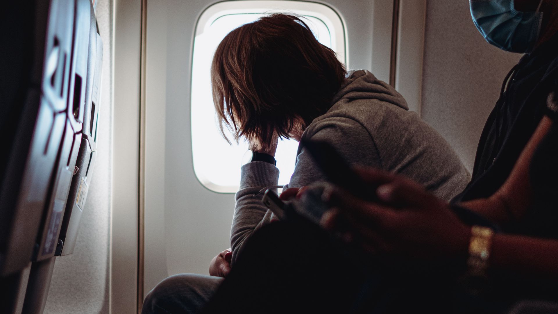 A passenger gazes out of an airplane window, reflecting on in-flight travel.