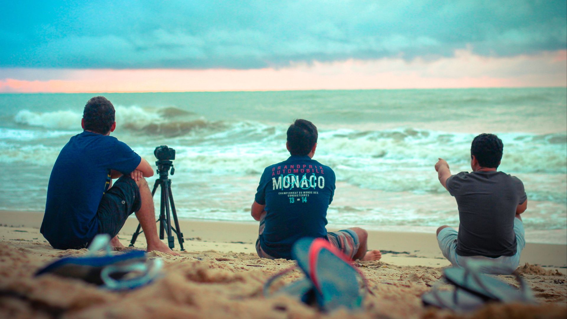 A serene moment on Porto Seguro beach with three men enjoying the sunset by the ocean.