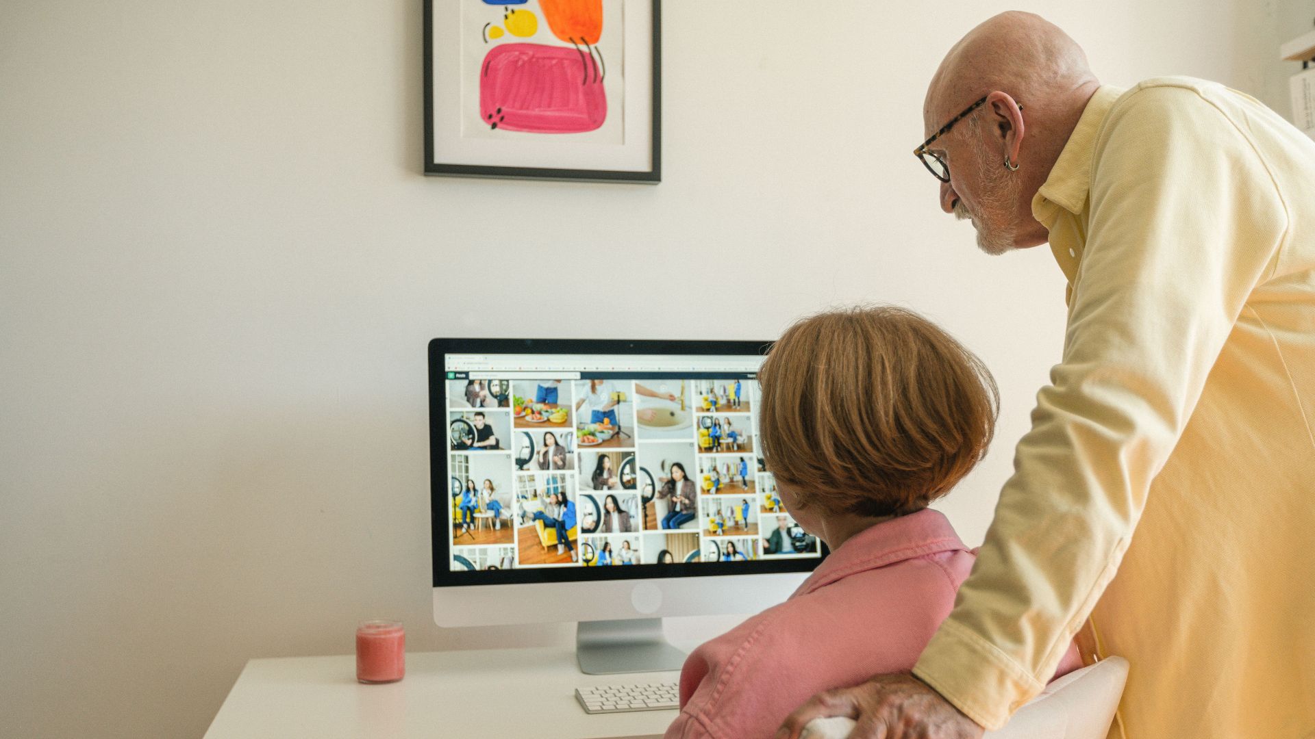 Senior couple enjoying browsing photos together at home on a desktop computer.