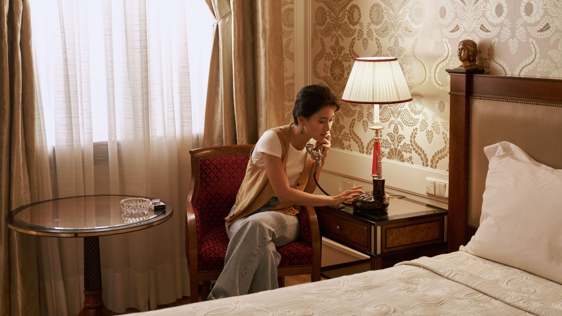 A woman talks on a vintage phone in a luxurious hotel room, creating a retro ambiance.
