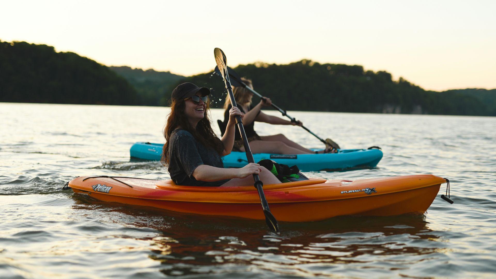 woman in blue shirt and blue denim jeans riding orange kayak on water during daytime