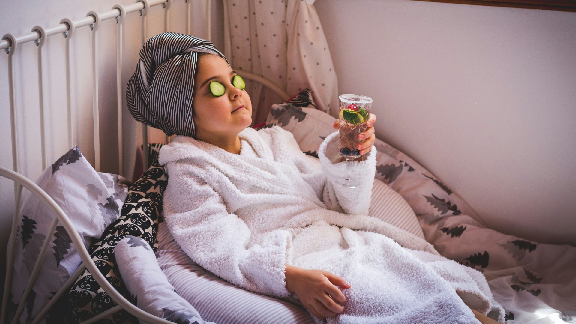 baby in white sweater and yellow goggles lying on bed