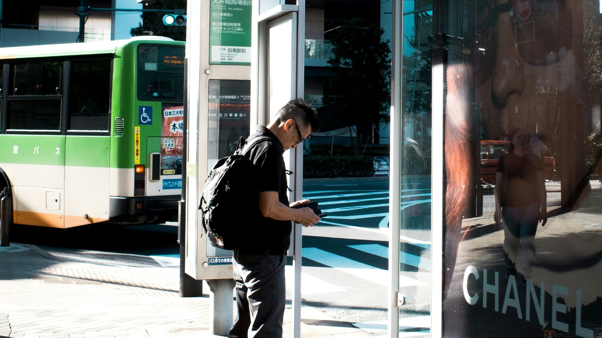 A man standing at a bus stop waiting for a bus