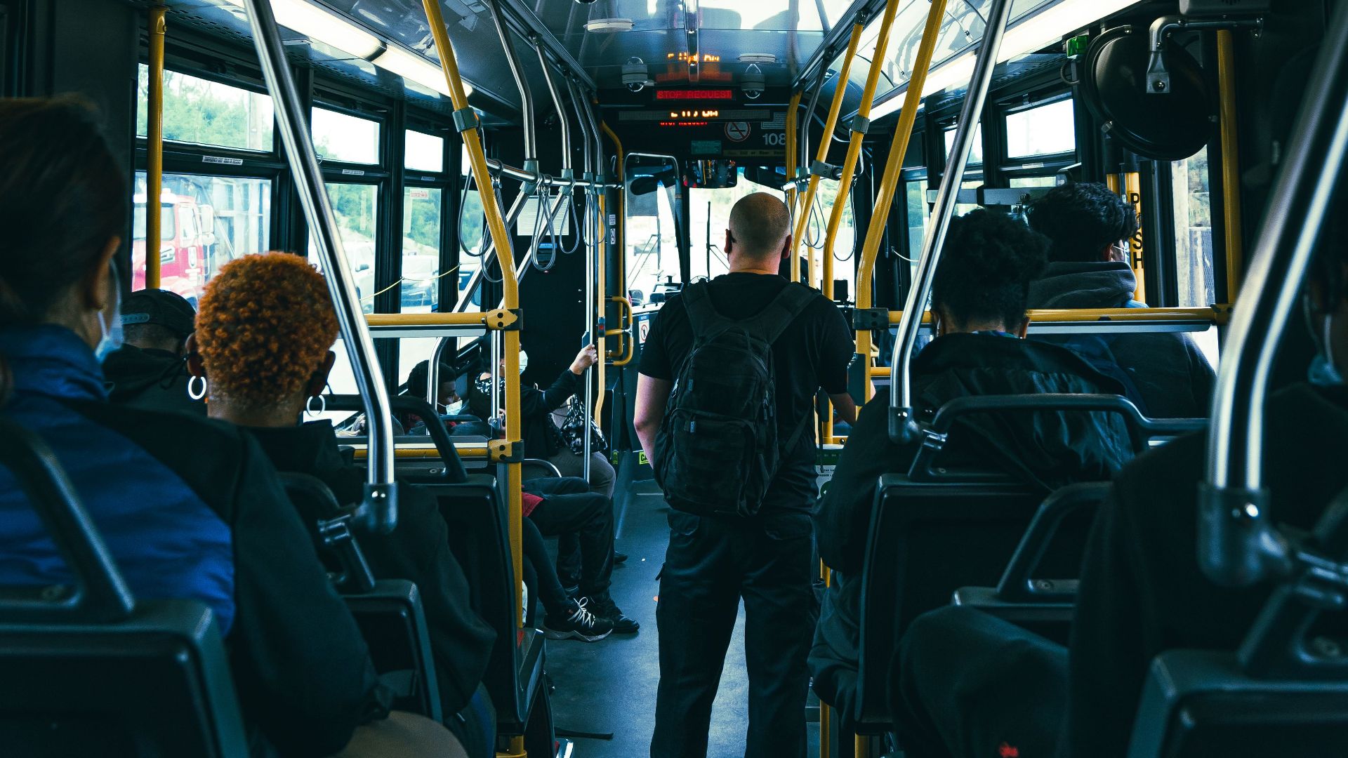 Urban public bus interior with diverse passengers commuting during the day.