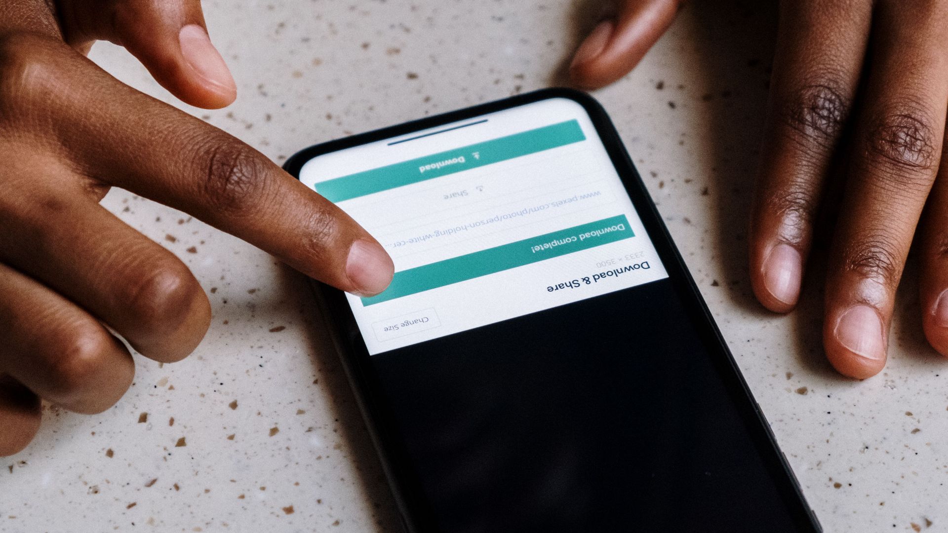 Close-up of hands interacting with a smartphone, displaying downloading interface.