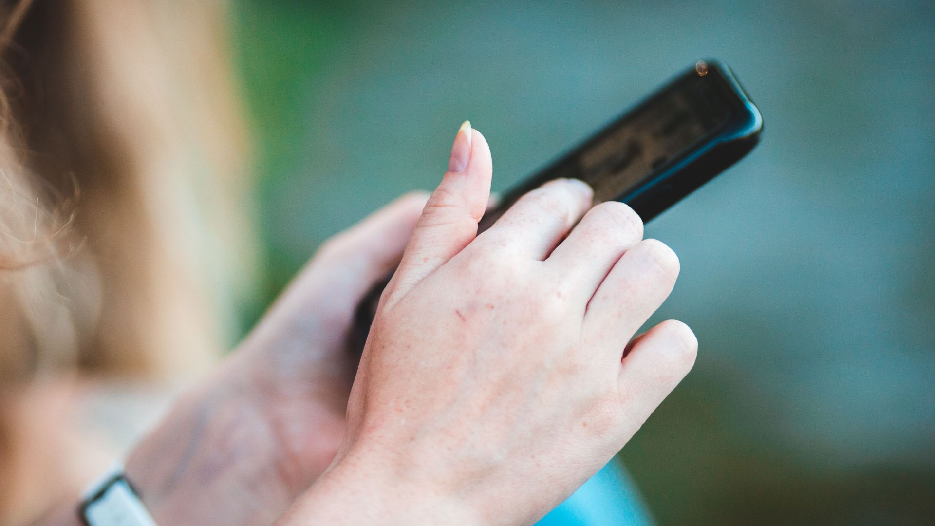 Hands holding a smartphone with blurred background, showcasing modern technology use.