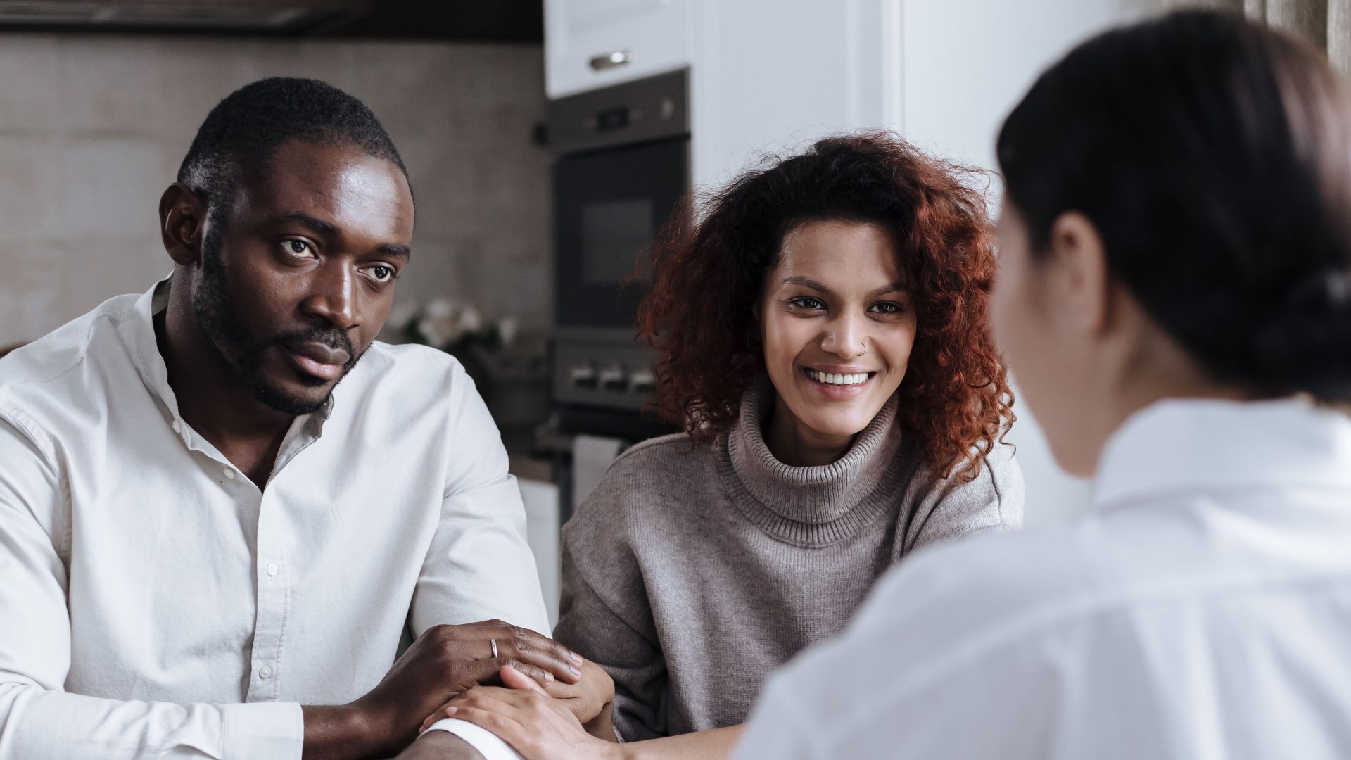 Happy couple consulting with a professional advisor in a home setting.