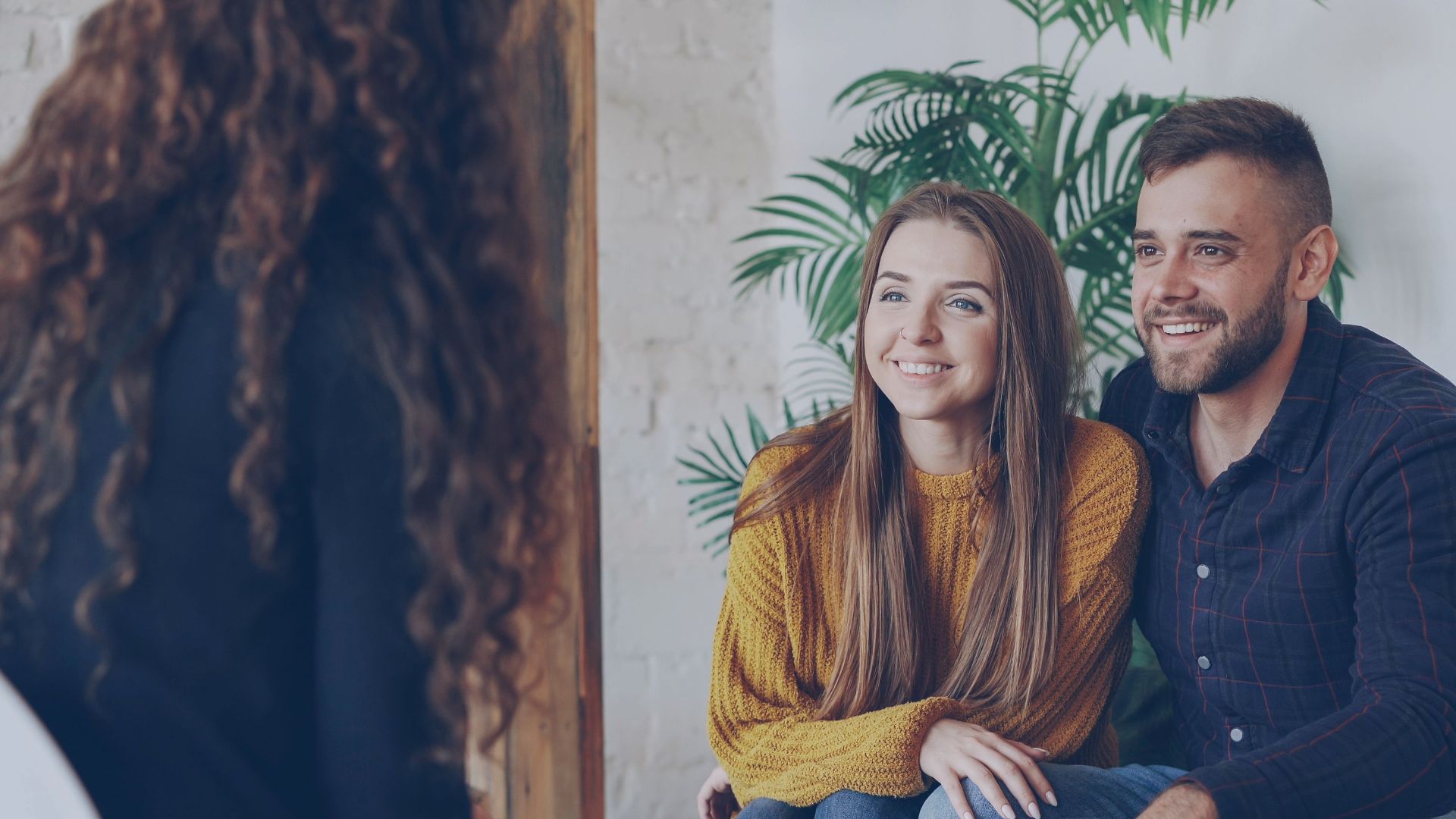 Couple discussing home options with agent in modern office setting.