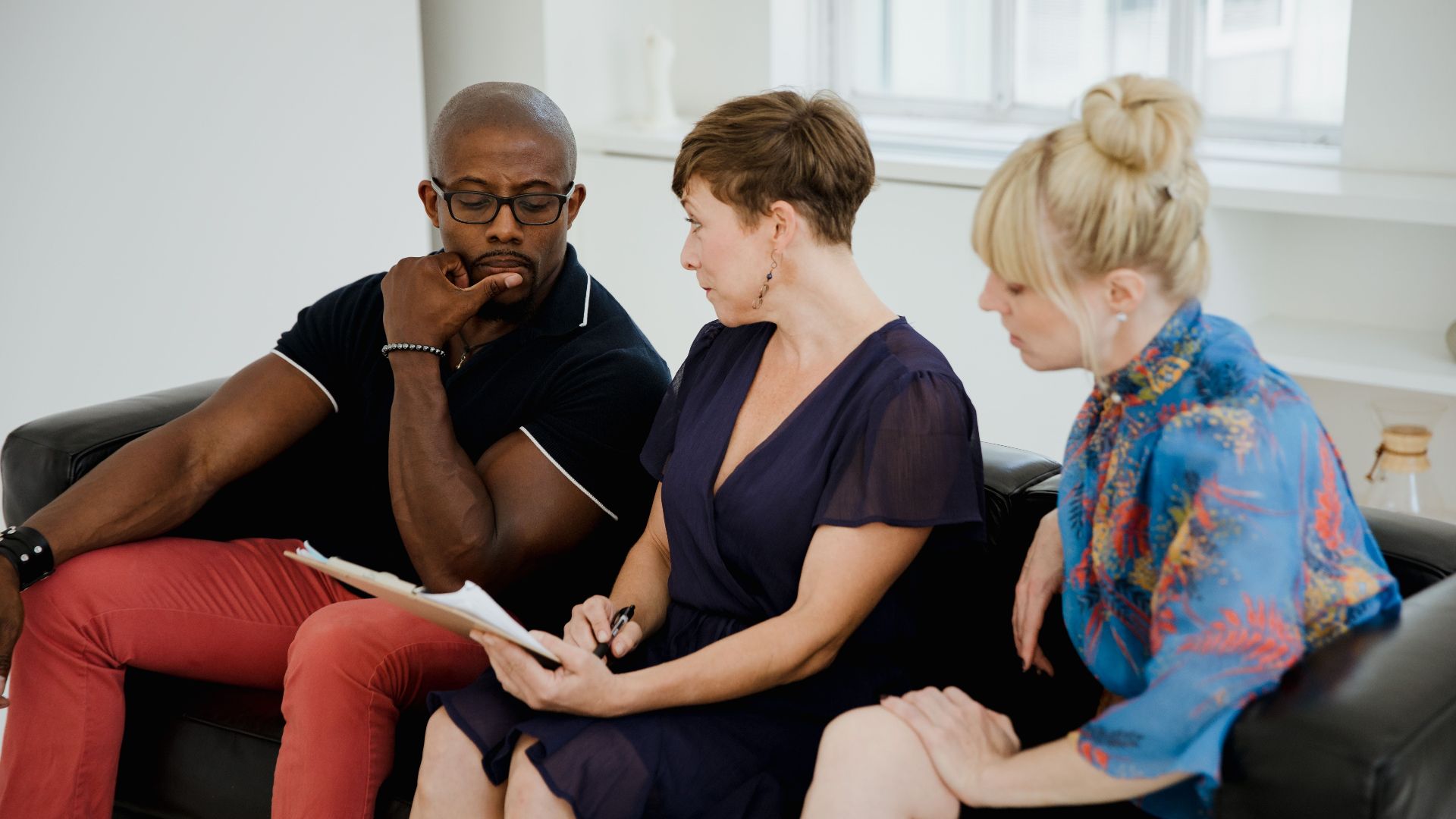 A diverse group of adults engaging in a thoughtful conversation indoors.