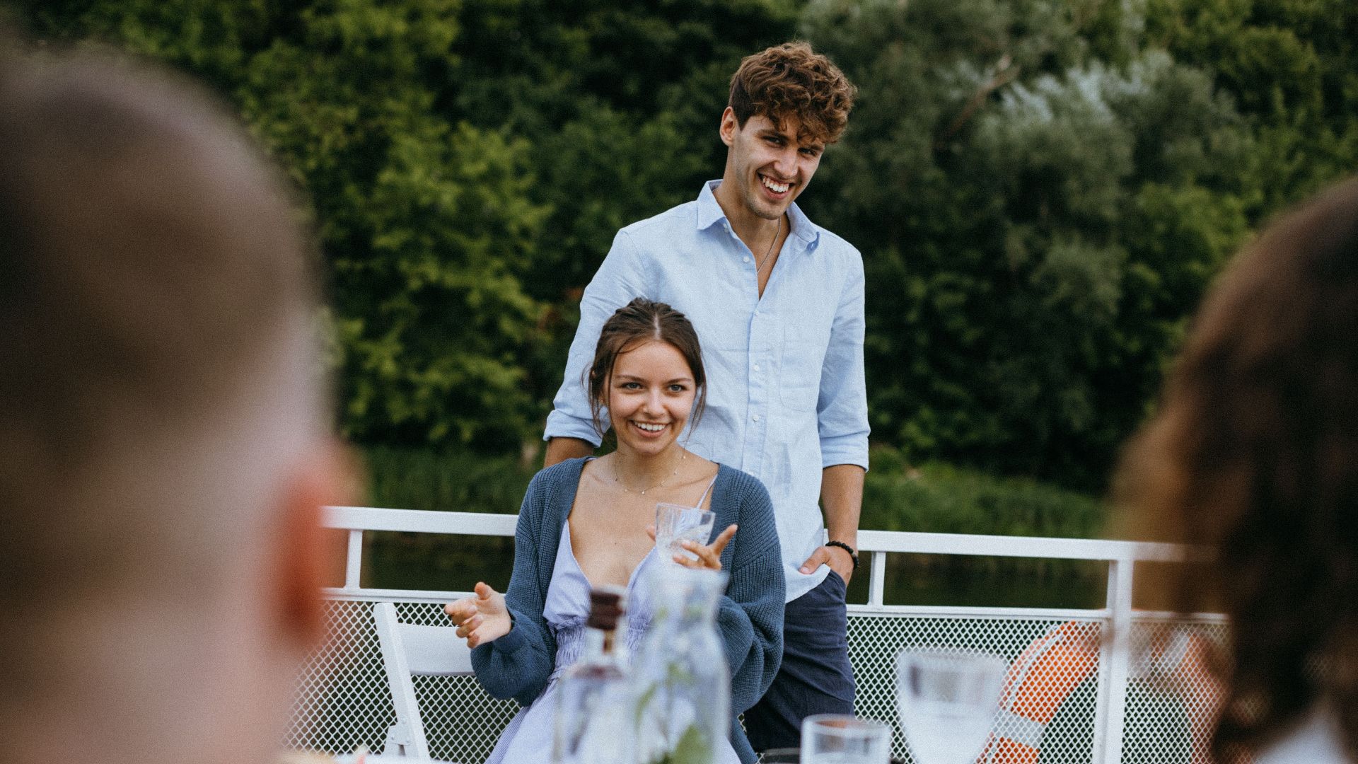 Cheerful young couple at an outdoor dinner with friends, enjoying lively conversation and good company.