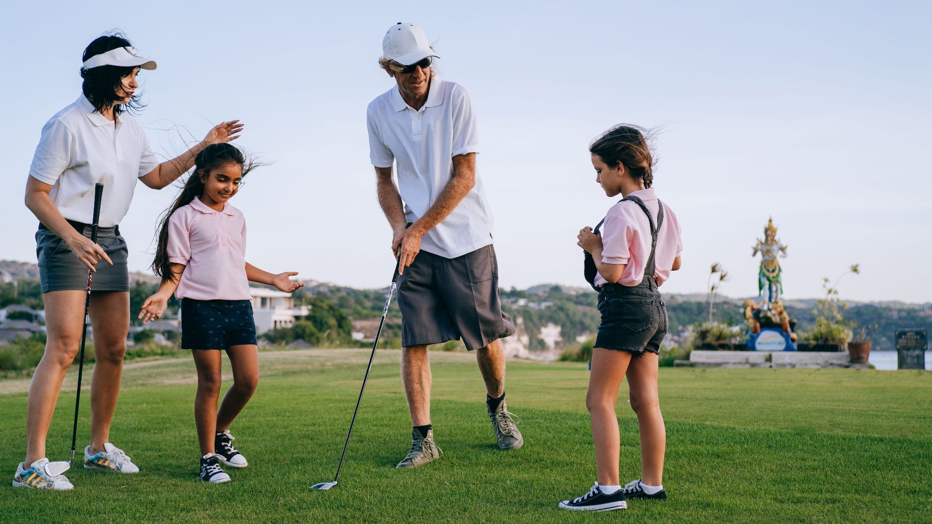 A family of four playing golf together on a sunny day, enjoying quality time outdoors.