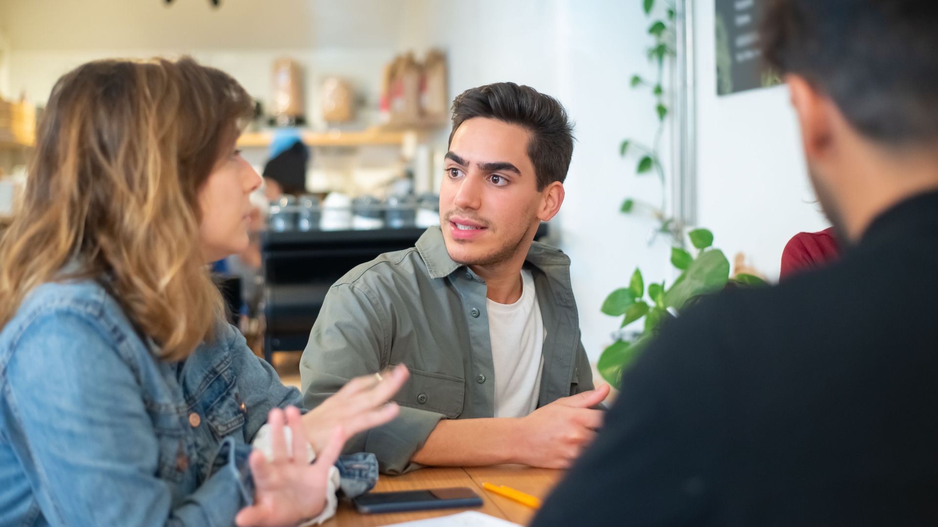 Young adults engaging in a lively discussion at a cozy café setting.