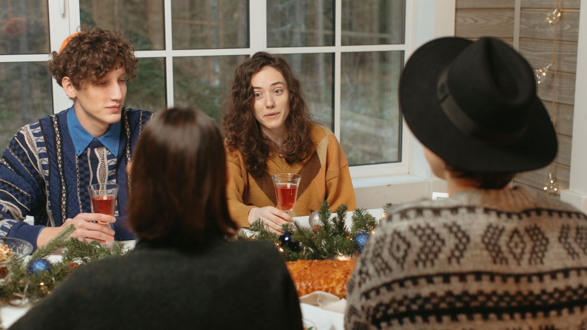 A group of friends enjoying a festive holiday meal with drinks and decorations.