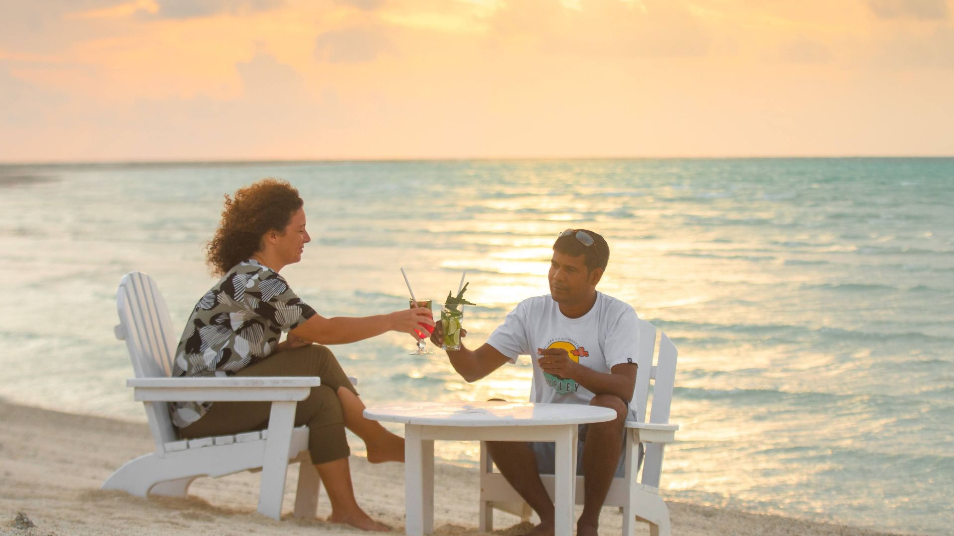 Couple enjoying a sunset drink at a beachside setting in the Maldives, perfect for a tropical getaway.