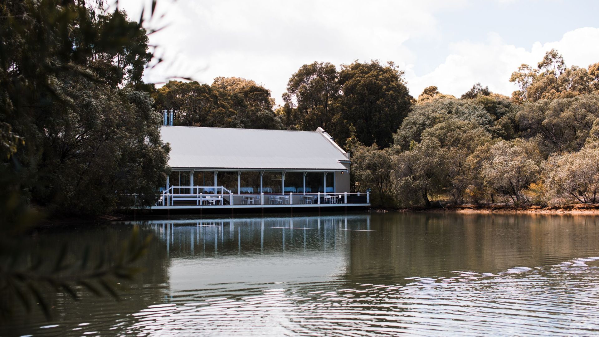 Building exterior against lake with rippling water surrounded by lush trees under cloudy sky in Florida