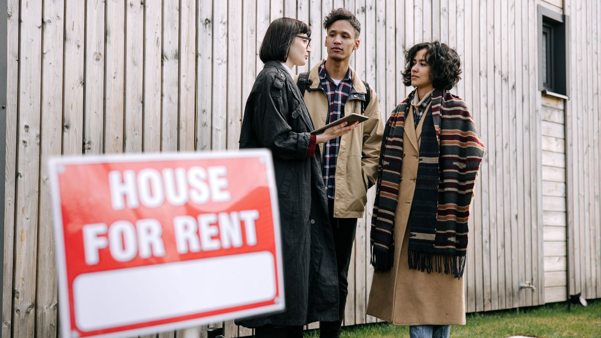 An interracial couple meets with a real estate agent to inquire about a house for rent.