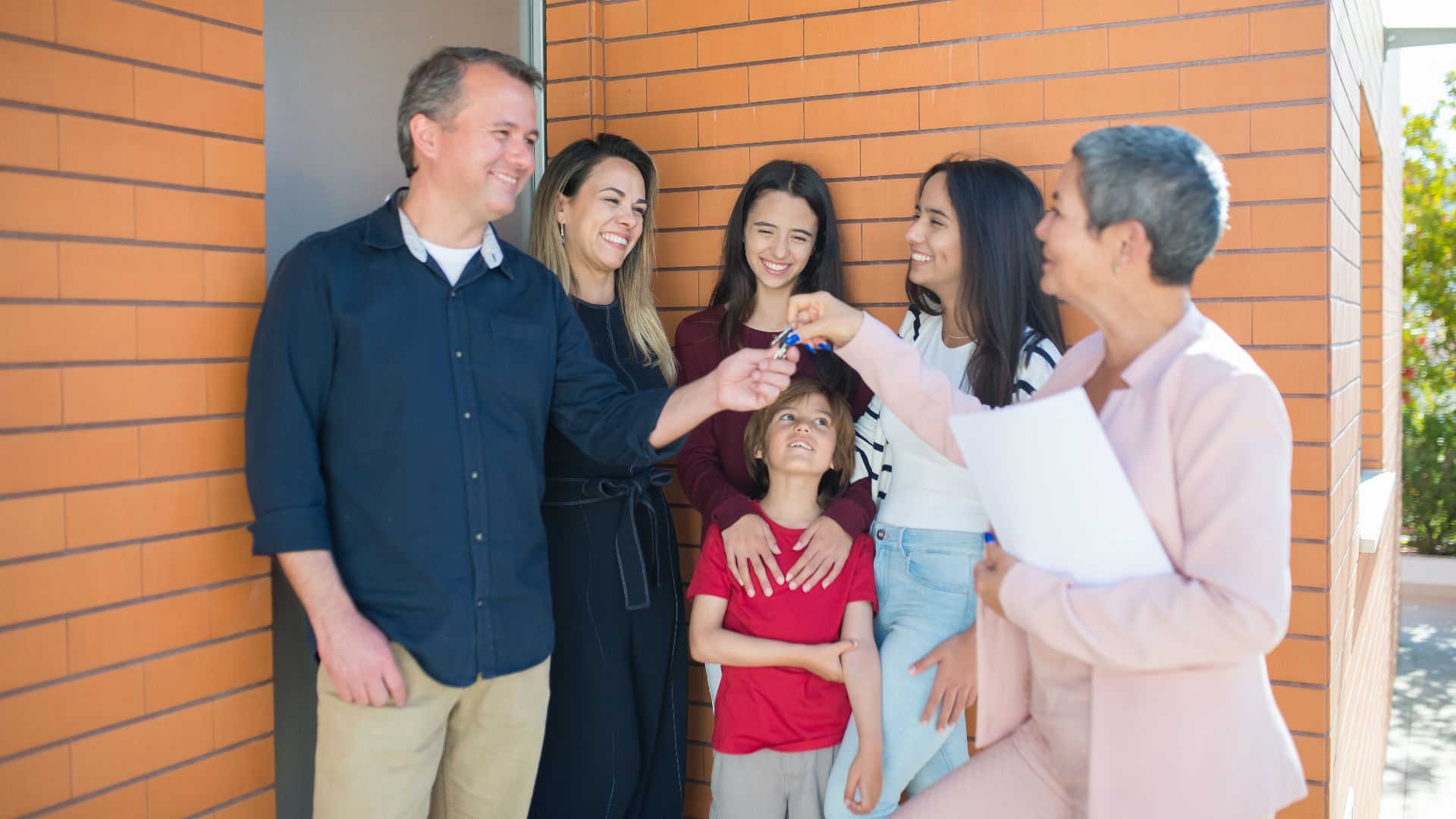 Family joyfully receiving keys to their new home outdoors, symbolizing real estate success.