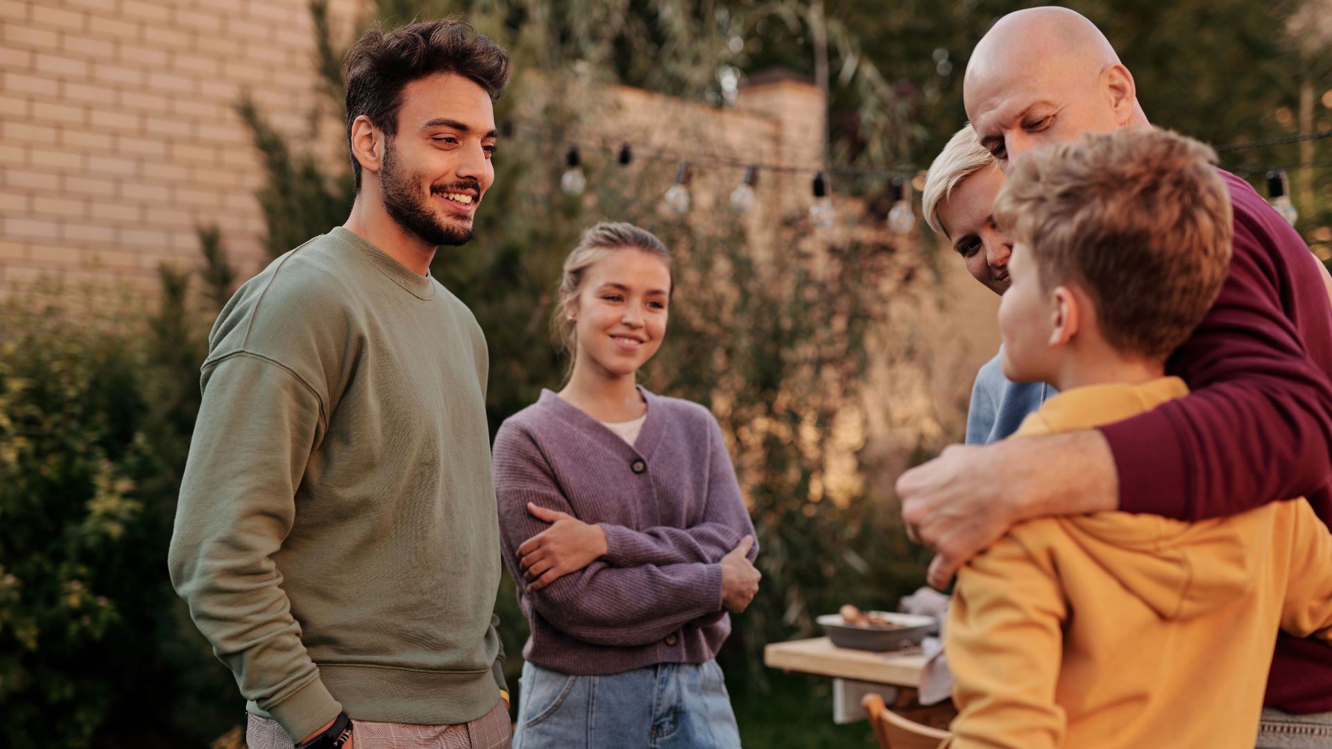 Group of cheerful multiracial relatives smiling and communicating in yard during meeting in summer weekends