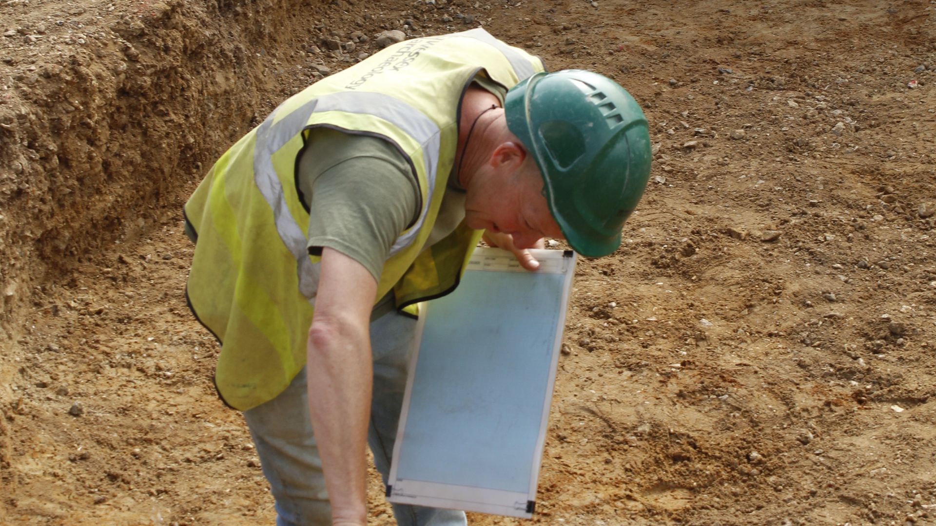 Archaeologist measuring a trench face for drawing at Matthew Arnold School, Staines-upon-Thames, Surrey, April 2019 and June 2021