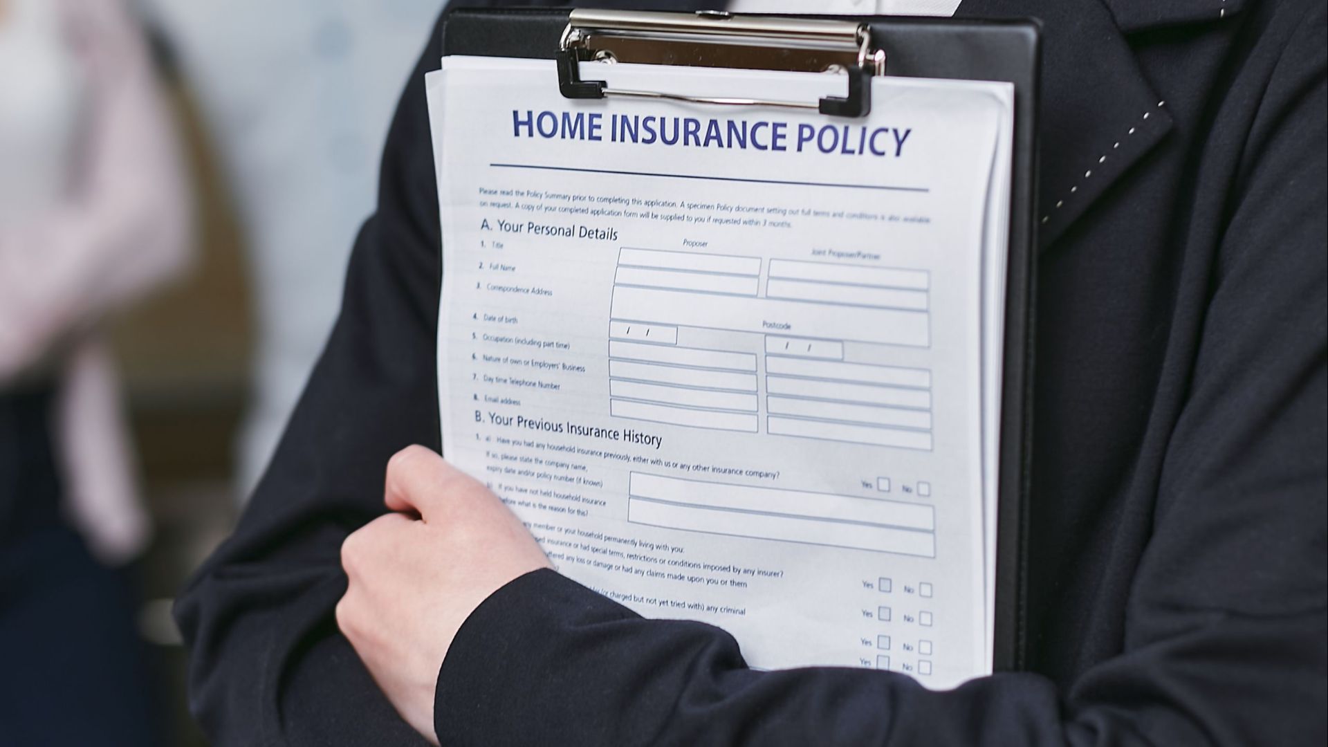 Close-up of a person holding a home insurance policy on a clipboard, captured indoors.