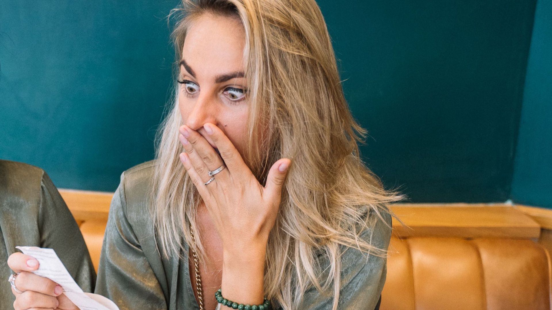 Two women express surprise while reviewing a restaurant bill in a casual setting.