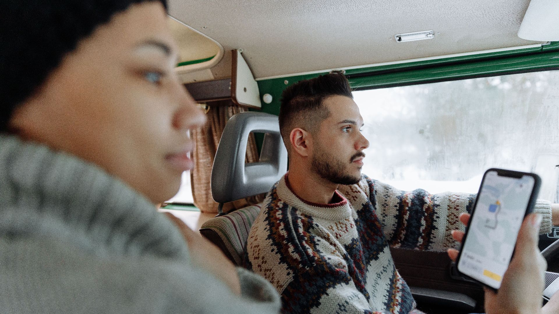 Couple using navigation app in a vintage campervan during a road trip.
