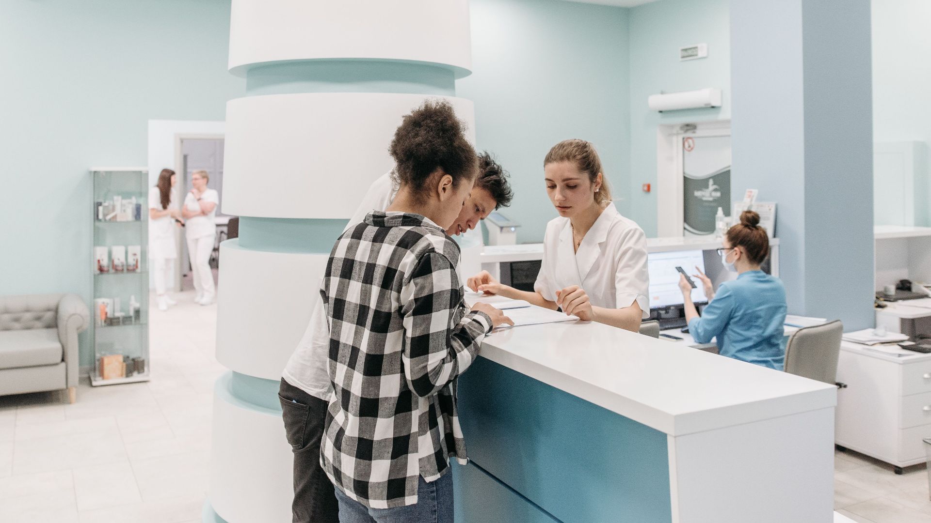 Bright, welcoming clinic reception with patients interacting with staff for registration.