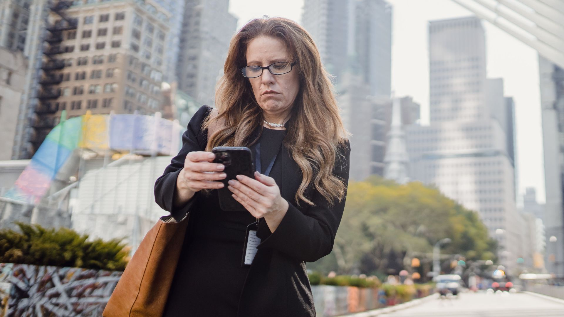 Businesswoman on phone in city street against modern skyscrapers.