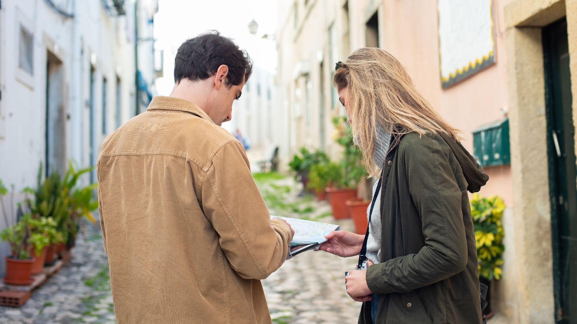 Two travelers exploring a charming European street, using a map for navigation.