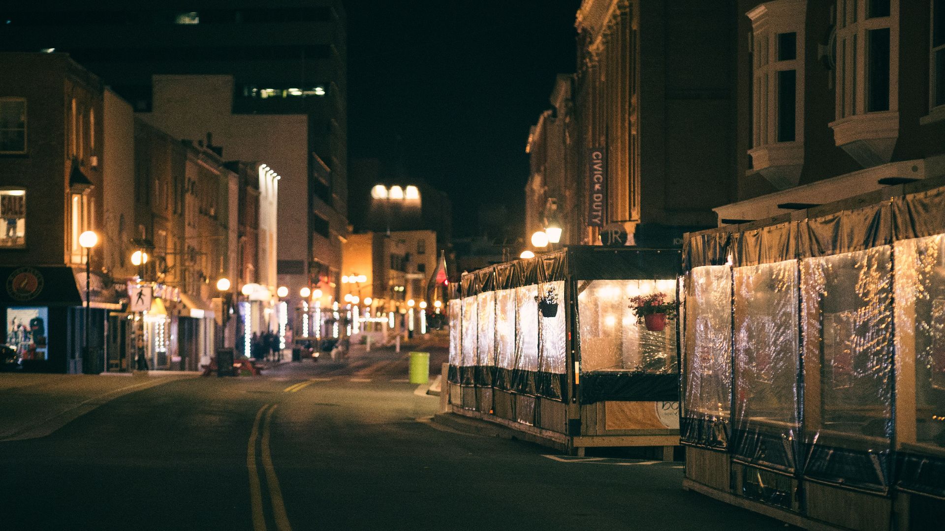 A quiet and illuminated urban street scene captured at night with decorative lights.