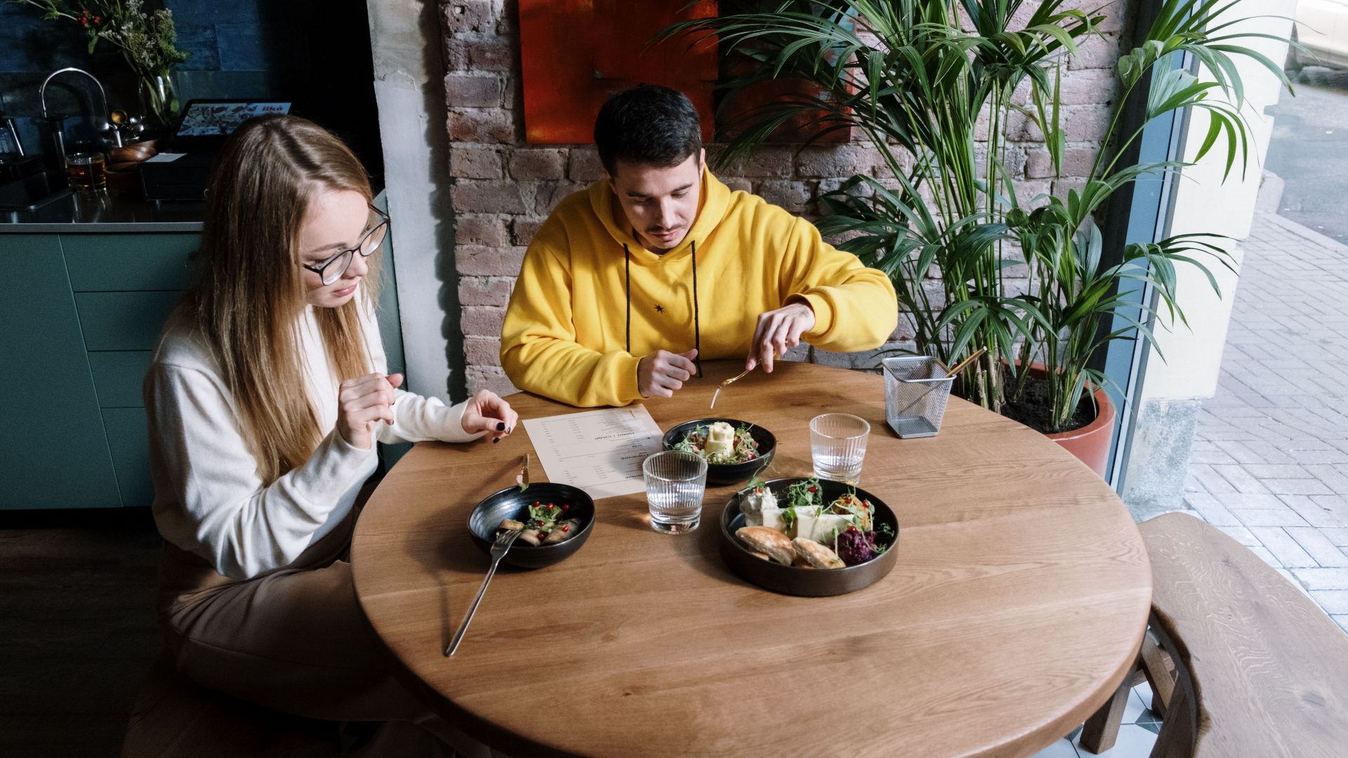 A young couple enjoys a casual meal at a modern indoor restaurant setting.