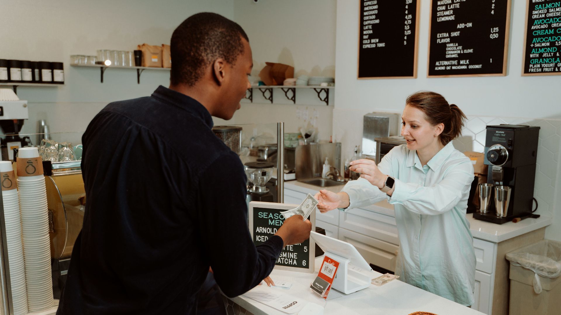A customer pays for coffee at a café counter, transaction with barista.