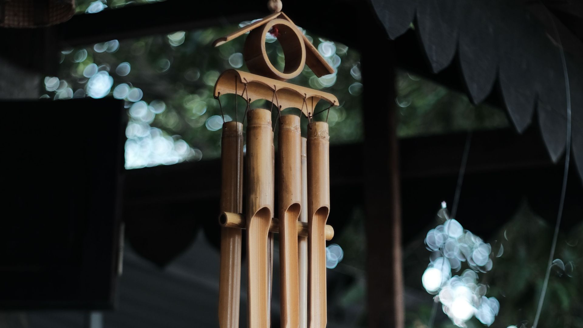 Close-up of bamboo wind chimes hanging outdoors with natural backdrop.